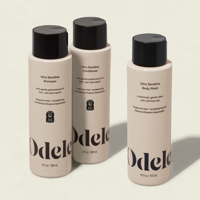 Three beige bottles from the Odele Ultra Sensitive Set—shampoo, conditioner, and body wash—stand upright on a light background. Their labels highlight that they are ultra sensitive and fragrance-free.