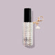 The Touch-Ups To Go Bundle features a cylindrical lip balm with a black cap in a beaded, transparent case and a gold keychain with a cloud charm—perfectly paired with your Hair Oil Mini—set against a pale lavender background.