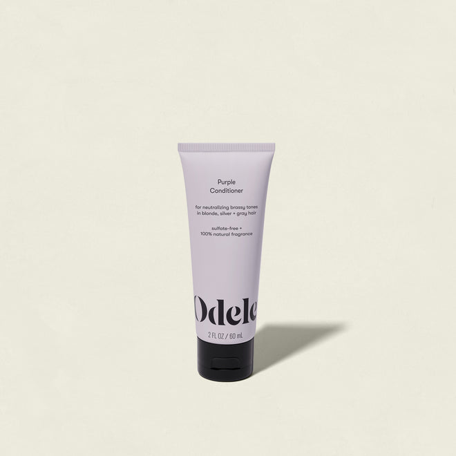 The Odele Purple Conditioner Mini with a black cap stands upright on a light beige background. The label highlights that it is sulfate-free and ideal for neutralizing brassy tones in blonde, silver, or gray hair.