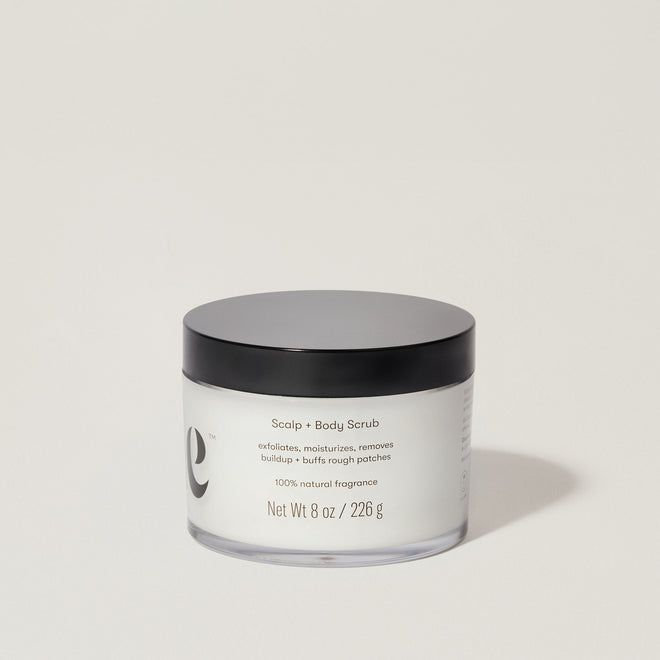 A jar of Odele Scalp & Body Scrub stands upright against a plain, light-colored backdrop with the back of the label facing the camera.