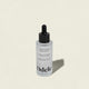 A bottle of Rejuvenating Scalp Serum with a black dropper cap sits on a light beige background. The label notes this serum nourishes the scalp and supports hair density.