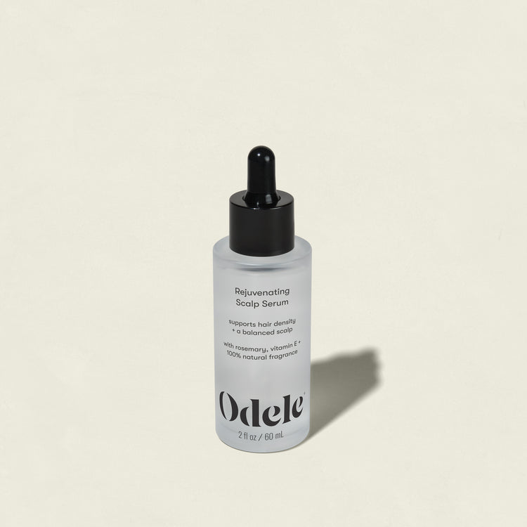 A bottle of Rejuvenating Scalp Serum with a black dropper cap sits on a light beige background. The label notes this serum nourishes the scalp and supports hair density.