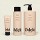 Three beige Volumizing Shampoo Bulk bottles from Odele, in varying sizes, are shown side by side against a light background. Each features black text and lids or pump tops, emphasizing their weightless moisture formula.