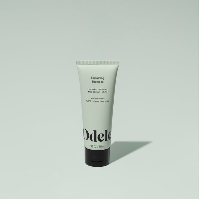 A tube of Odele Smoothing Shampoo stands upright against a plain, light green backdrop with the front of the label facing the camera.