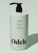 A light green 32 fl oz (946 ml) bottle of Odele Smoothing Conditioner Bulk with a black pump, highlighting moisture, frizz control, added shine, a sulfate-free formula, and 100% natural fragrance.