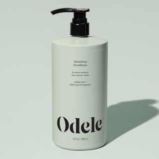 A light green 32 fl oz (946 ml) bottle of Odele Smoothing Conditioner Bulk with a black pump, highlighting moisture, frizz control, added shine, a sulfate-free formula, and 100% natural fragrance.