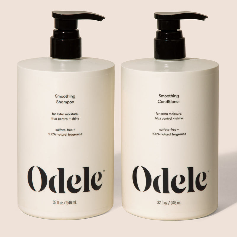 Two bottles of Odele Smoothing Shampoo and Conditioner stands upright against a plain, light-colored backdrop with the front of the label facing the camera.