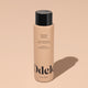 A bottle of Odele Thickening Shampoo stands upright against a plain, light orange backdrop with the front of the label facing the camera.