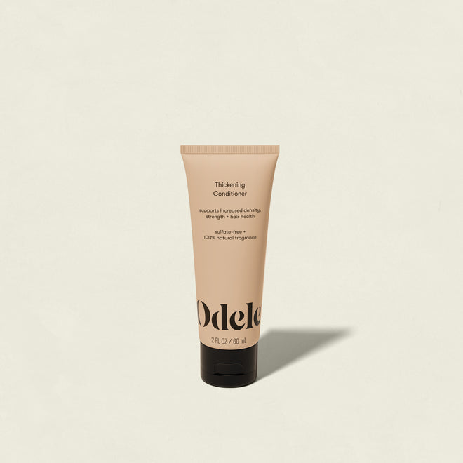 A beige tube of Odele Thickening Conditioner Mini (2 fl oz/59 mL) stands upright on a light background, with a label highlighting benefits for thinning hair: improved density, strength, and overall hair health.