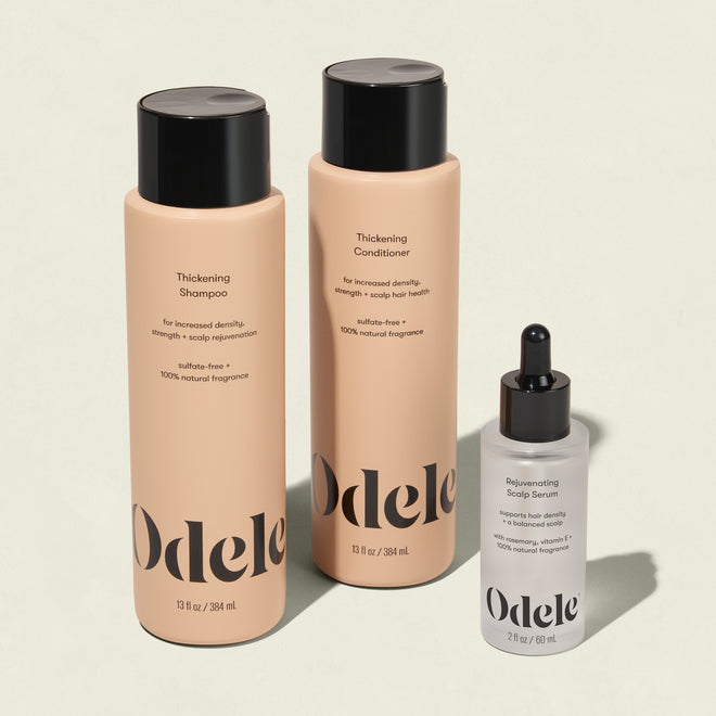 The Odele Thickening Set includes thickening shampoo and conditioner in tall beige bottles with black caps, plus a rejuvenating scalp serum in a small clear bottle with a black dropper cap.