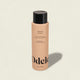 A peach-colored bottle of Odele Thickening Shampoo with a black cap rests on a light background, its label highlighting increased density, strength, and scalp rejuvenation.