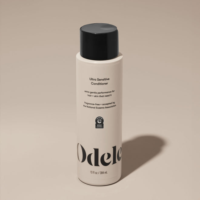A bottle of Odele Ultra Sensitive Conditioner stands upright against a plain, light-colored backdrop with the front of the label facing the camera.