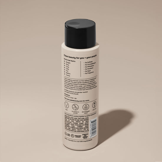 A bottle of Odele Ultra Sensitive Conditioner stands upright against a plain, light-colored backdrop with the back of the label facing the camera.