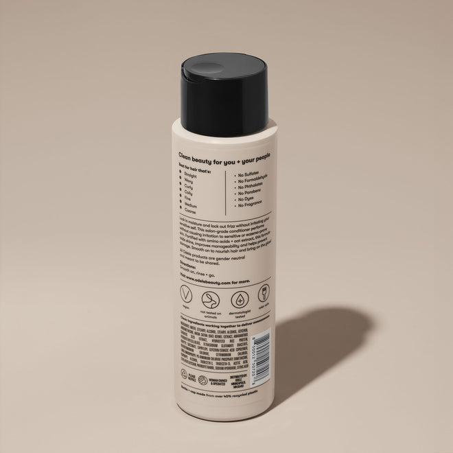 A bottle of Odele Ultra Sensitive Conditioner stands upright against a plain, light-colored backdrop with the back of the label facing the camera.