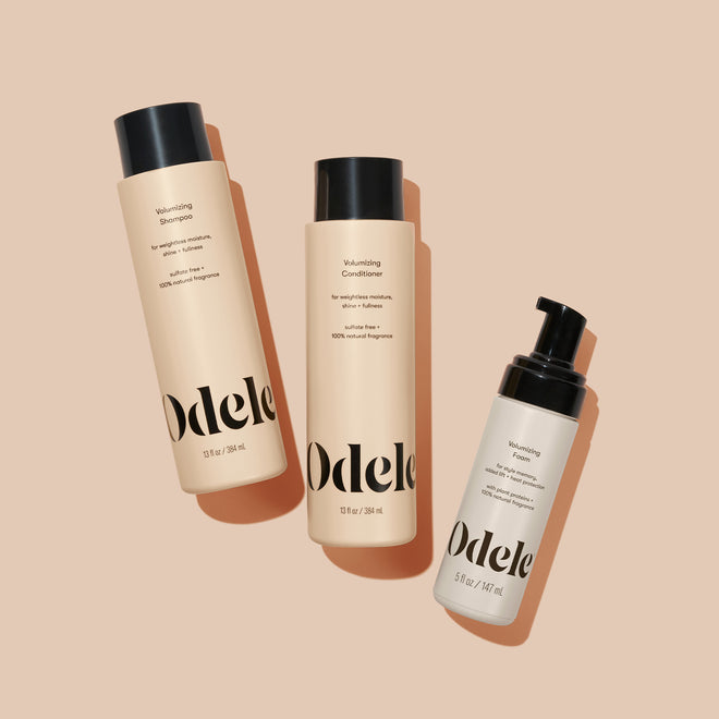 The Odele Volumizing Set lays against a plain, light orange backdrop with the front of the labels facing the camera.