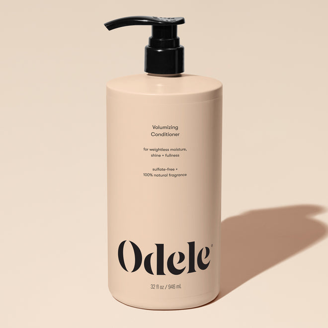 A beige bottle of Volumizing Conditioner Bulk with a black pump, minimalist text highlighting volume and weightless moisture benefits (32 fl oz / 946 ml), set against a neutral background.