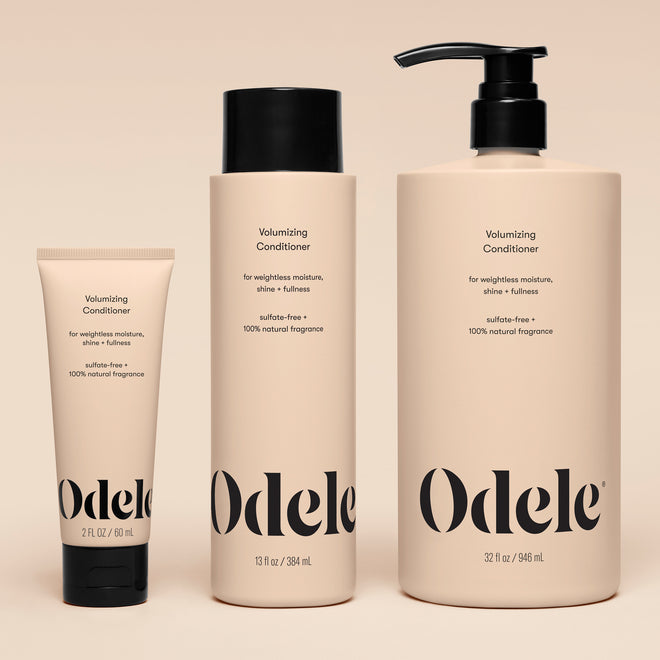 Three beige Volumizing Conditioner bottles in varying sizes with minimalist black text and pumps or caps stand upright on a neutral background, offering weightless moisture with salon-grade performance.