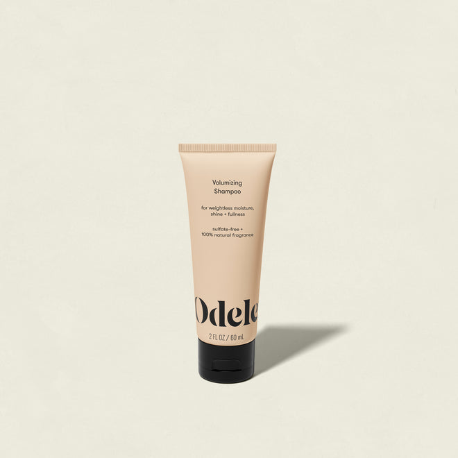 A beige tube of Odele Volumizing Shampoo Mini with a black cap is centered on a light background. This salon-grade, sulfate-free shampoo features 100% natural fragrance and delivers weightless moisture for fuller hair.