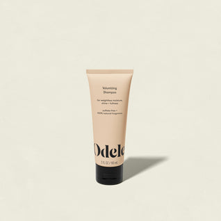 A beige tube of Odele Volumizing Shampoo Mini with a black cap is centered on a light background. This salon-grade, sulfate-free shampoo features 100% natural fragrance and delivers weightless moisture for fuller hair.
