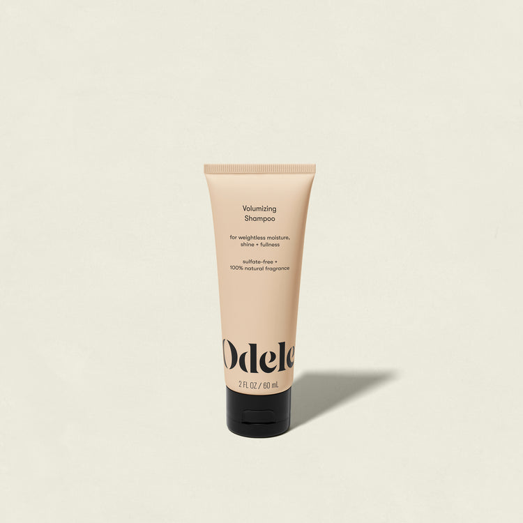 A beige tube of Odele Volumizing Shampoo Mini with a black cap is centered on a light background. This salon-grade, sulfate-free shampoo features 100% natural fragrance and delivers weightless moisture for fuller hair.
