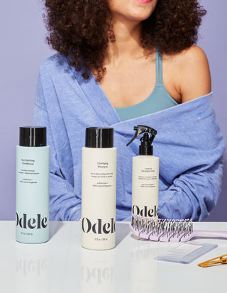 dark curly haired woman posing with hair products