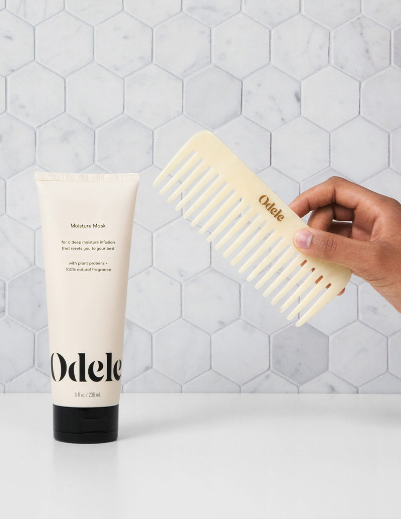 hand holding odele comb next to moisture mask bottle